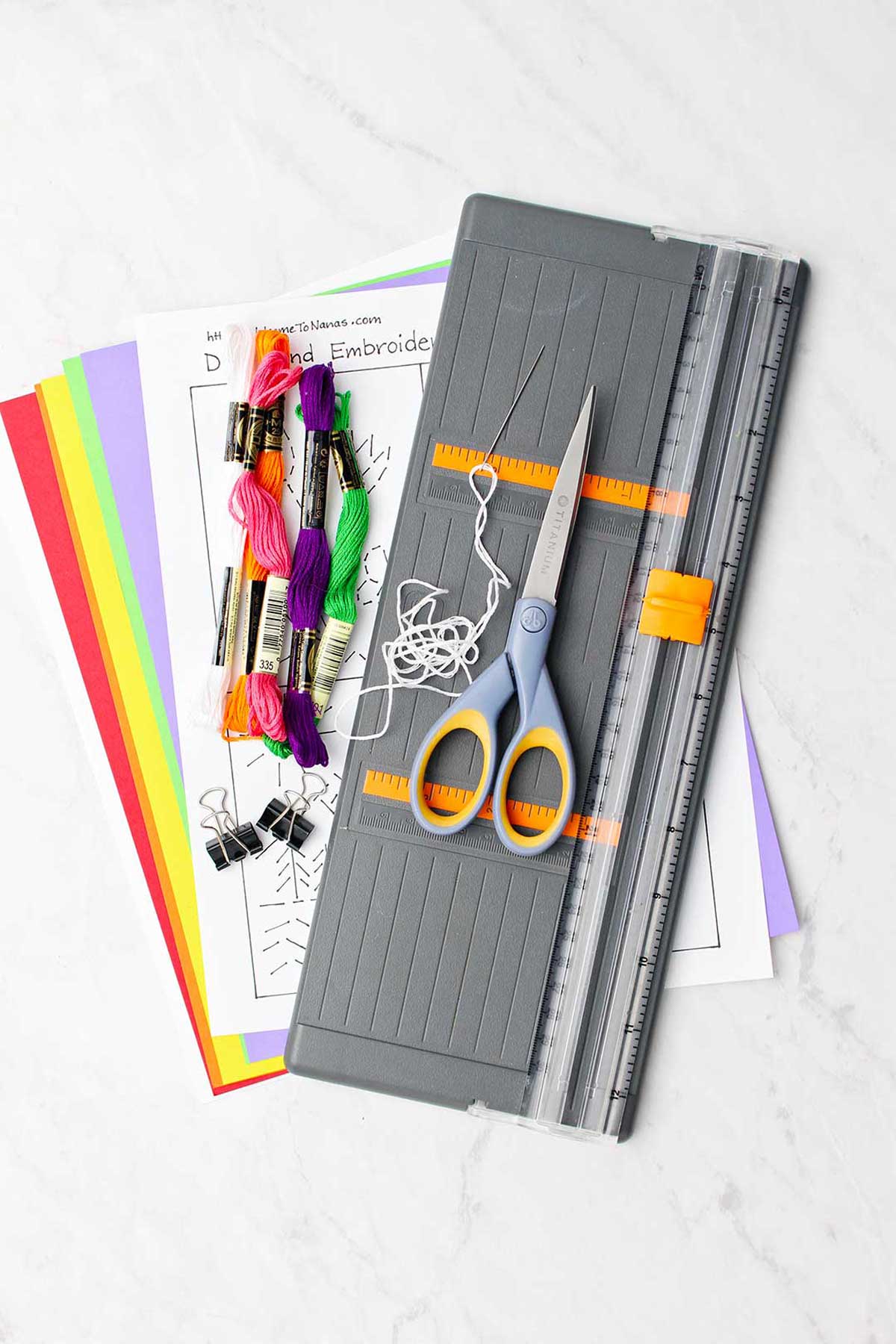 Materiais para cartão bordado à mão. Fios de bordado coloridos, papel, moldes, tesouras e cortador de papel.