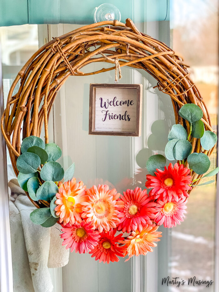 guirlanda de videira com flores laranjas e placa de boas-vindas para amigos