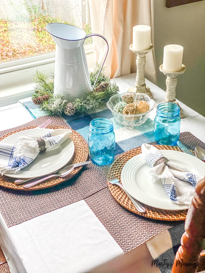 manta azul usada com detalhes azuis e louça branca sobre mesa de cozinha pequena