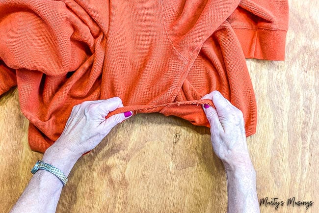 Rasgando um suéter laranja em tiras