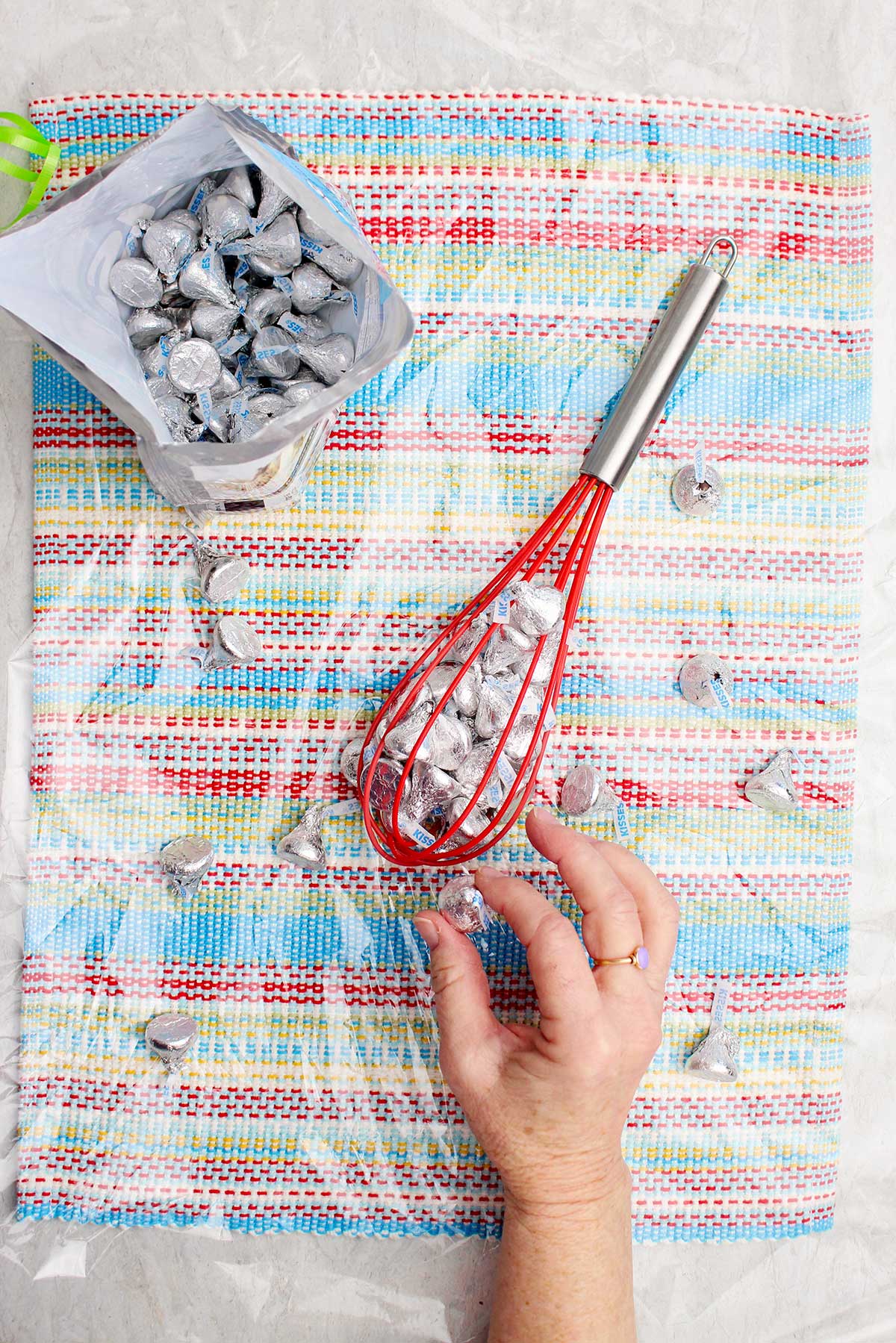 Pessoa colocando Hershey Kisses dentro de um batedor de silicone vermelho.