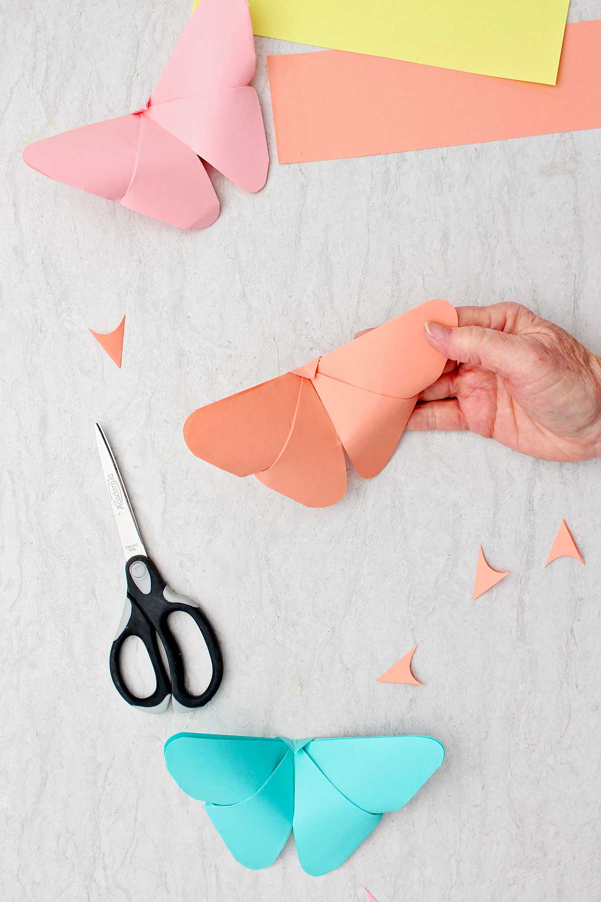 Uma borboleta de origami laranja completada com outras borboletas finalizadas ao lado.