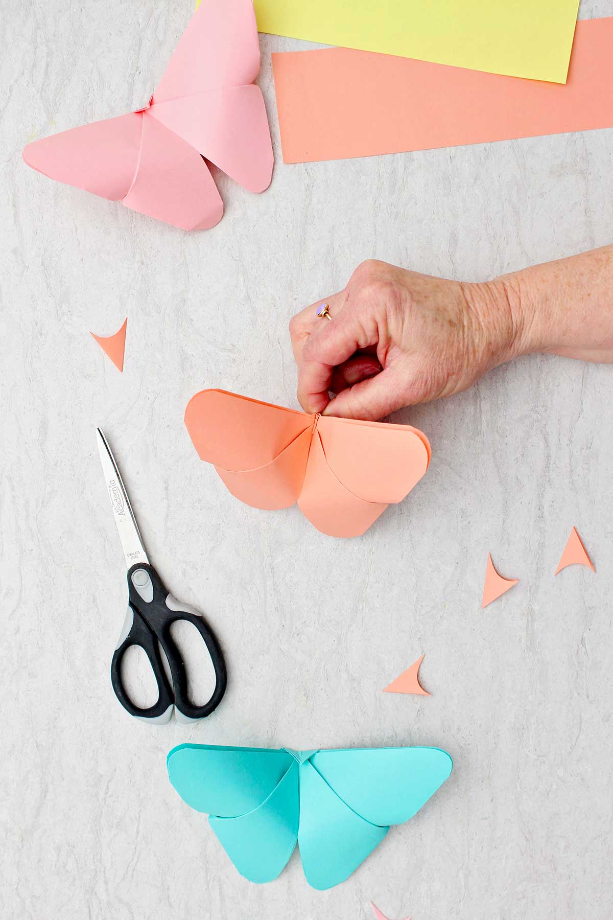 Uma borboleta de origami laranja completada com outras borboletas finalizadas próximas.