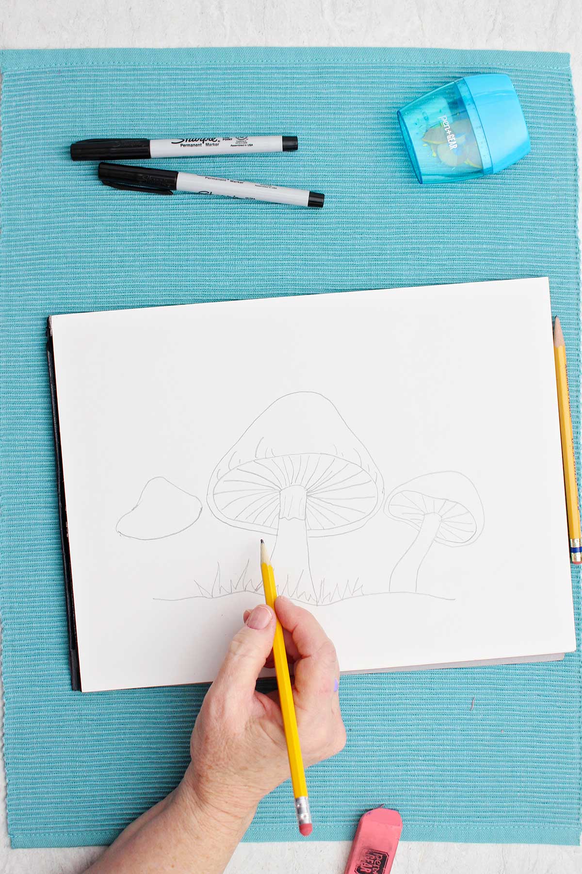 Um artista esboçando um desenho de um cogumelo com um lápis