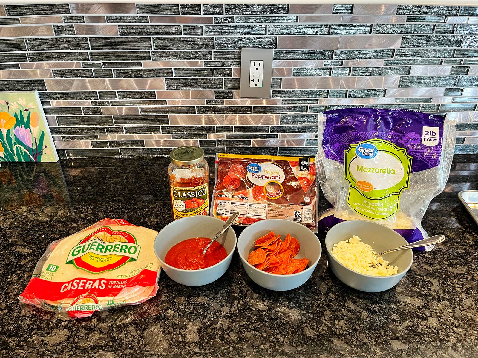 Materiais para fazer uma quesadilla de pizza em um balcão escuro de mármore.