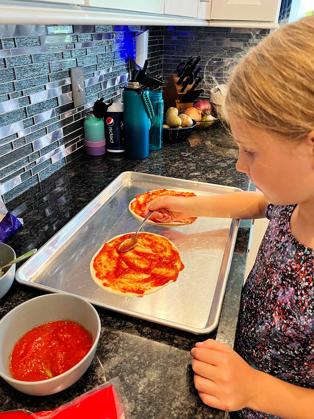 Uma criança colocando molho na quesadilla de pizza.