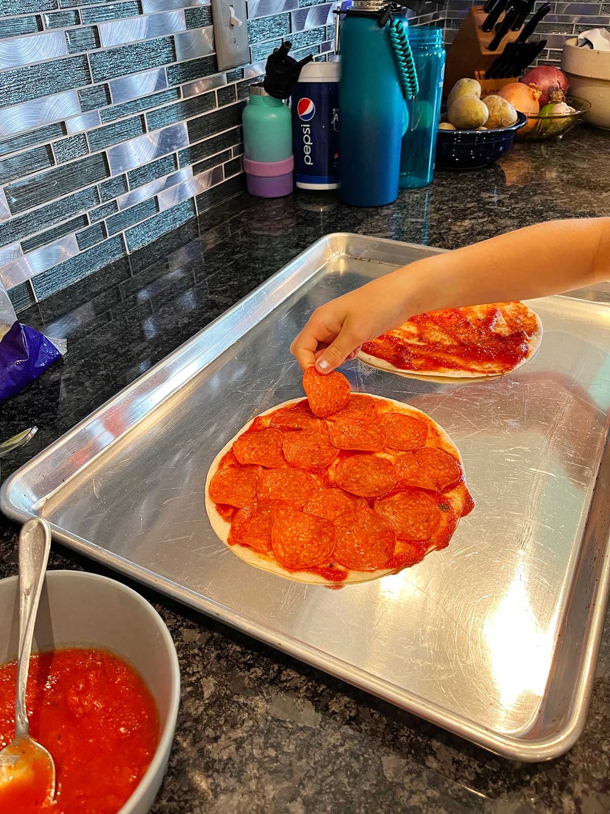 Uma criança colocando pepperoni na quesadilla de pizza.