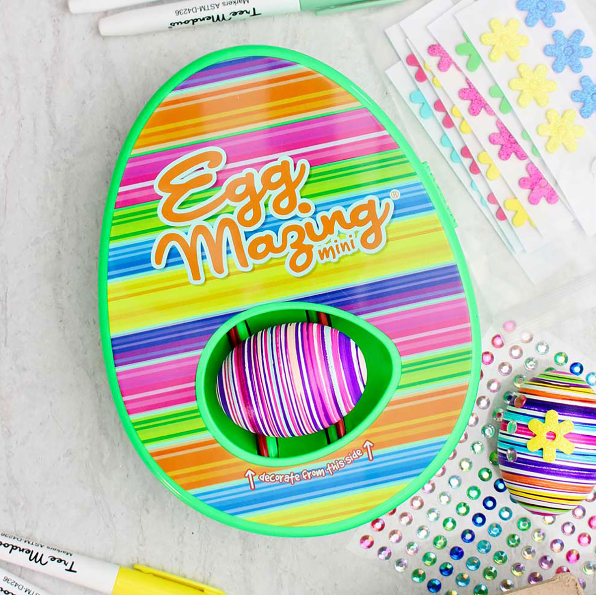 Kit de design listrado do EggMazing com ovo listrado colorido dentro e outros materiais próximos.