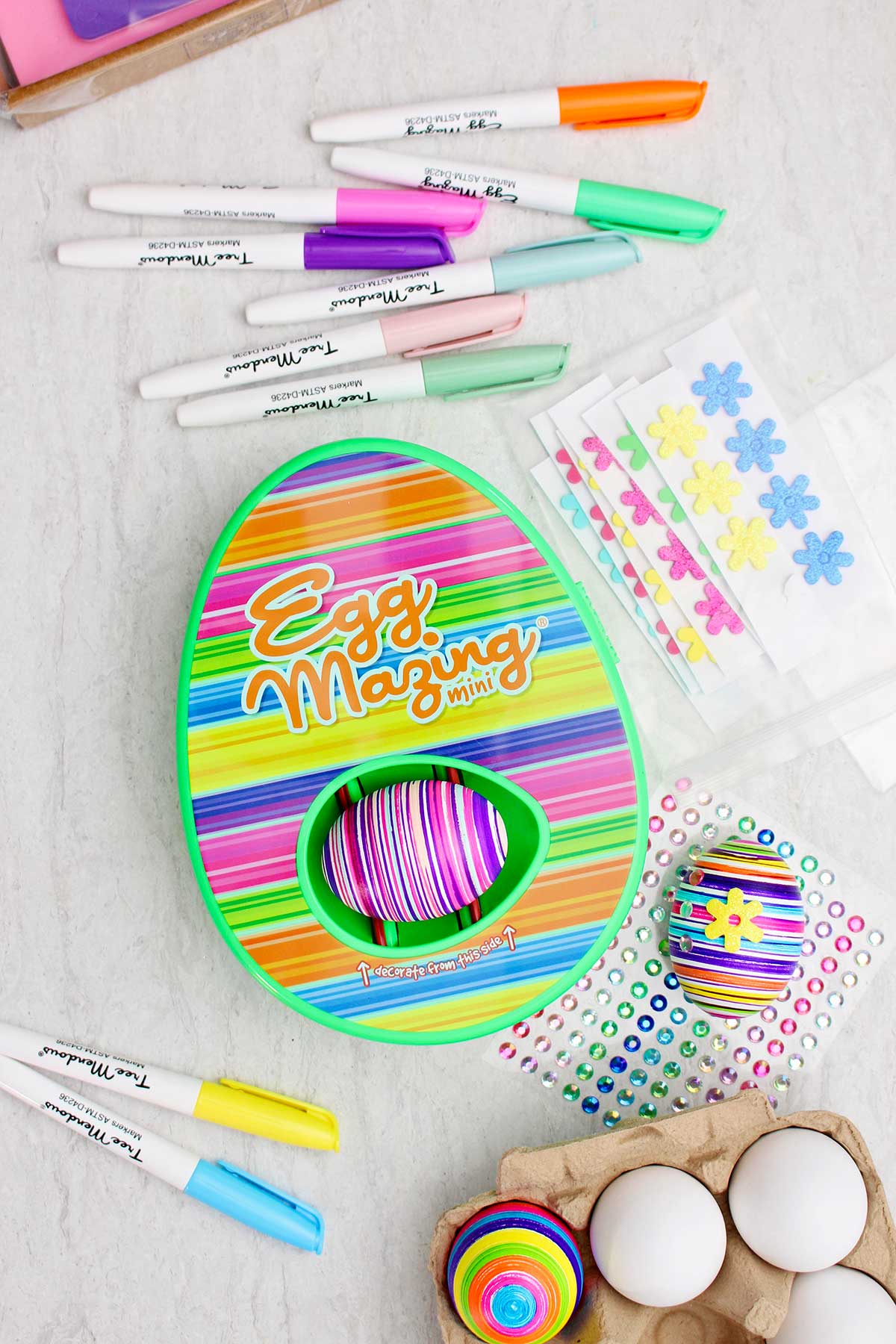 Kit de design listrado EggMazing com ovo colorido listrado dentro e outros suprimentos ao redor.