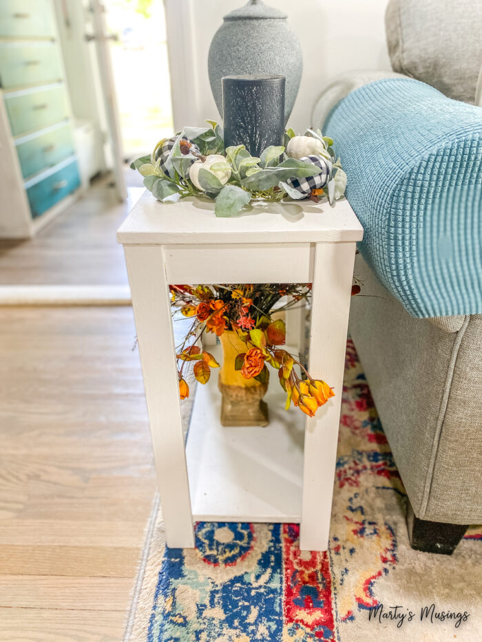 Pequena mesa branca com flores de seda sobre ela