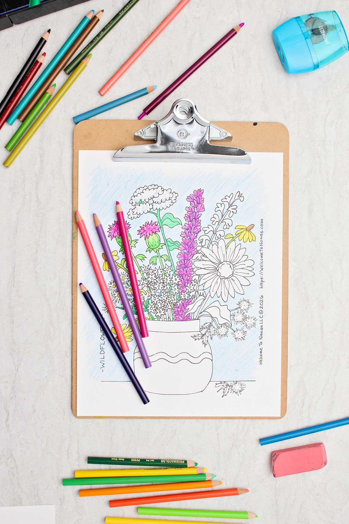 Uma página de colorir parcialmente completada de um buquê de flores silvestres em um vaso com lápis de cor ao redor.