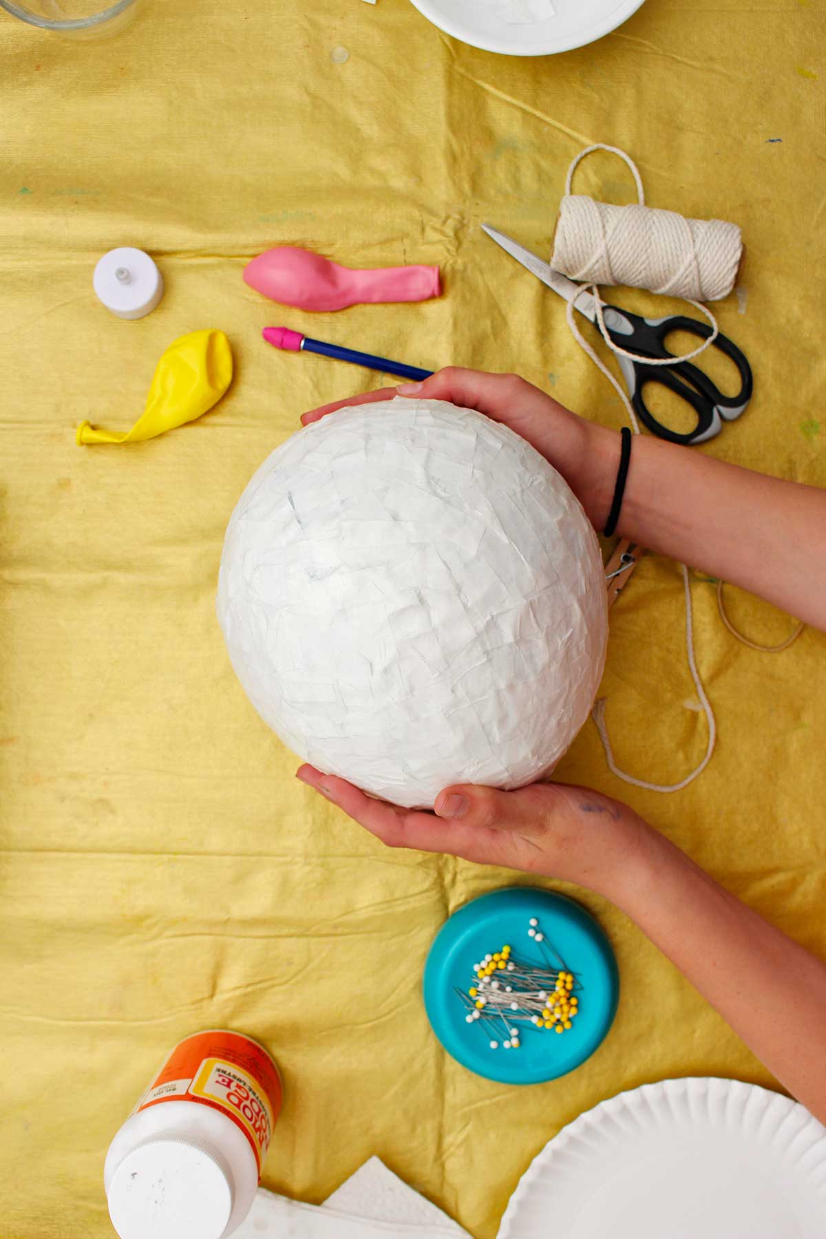 Pessoa segurando um balão de papel machê seco antes de pintar.