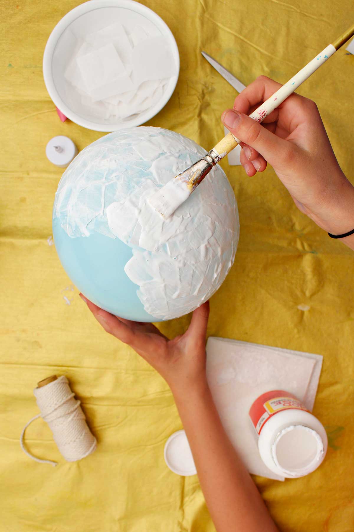 Pessoa pintando um balão azul com mod podge.