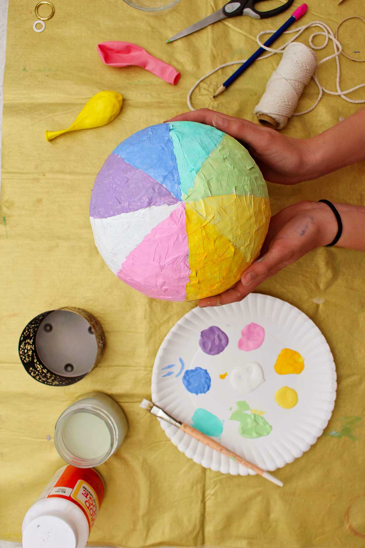 Pessoa mostrando um balão de ar quente pintado com listras de arco-íris pastel.