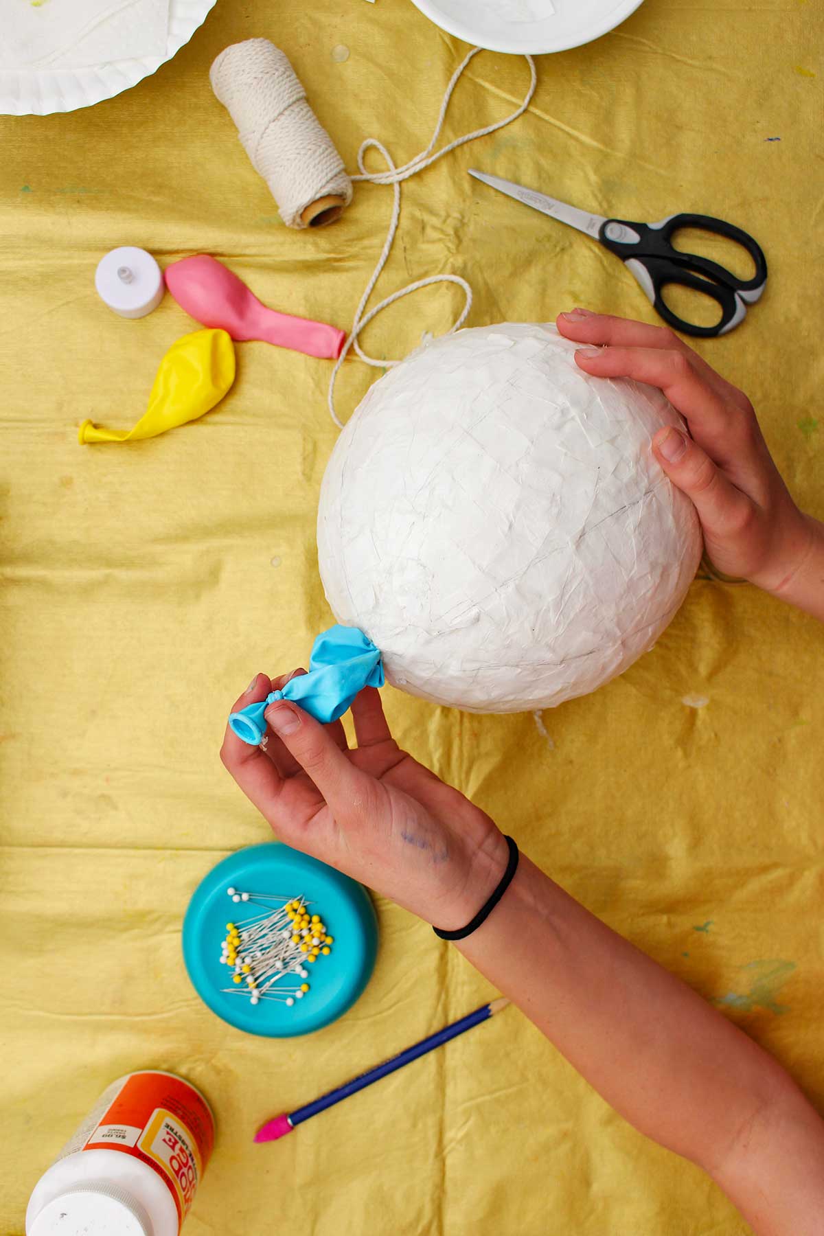 Pessoa puxando o balão estourado do final de um balão de papel machê seco.