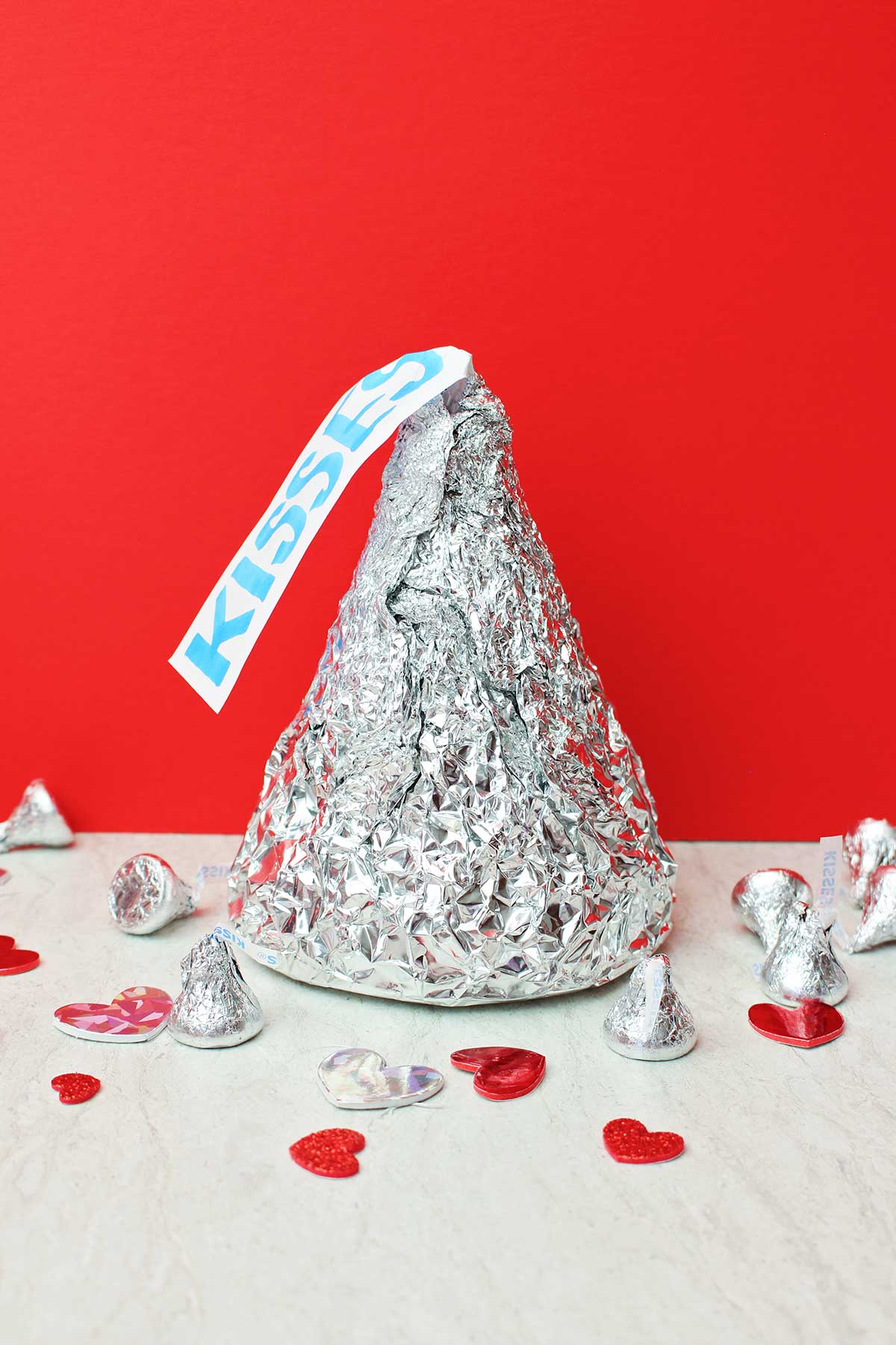 Beijo Gigante de Hershey com beijos de tamanho real e decorações de coração contra um fundo vermelho.