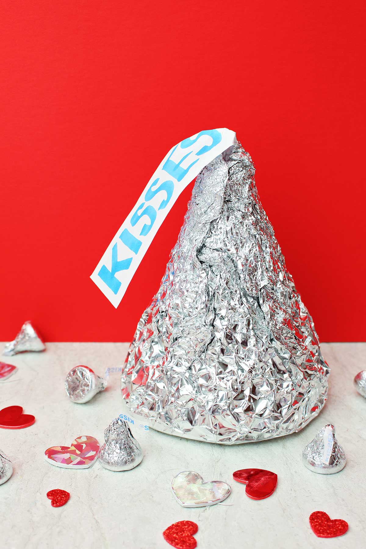 Gigante Beijo Hershey com beijos de tamanho real e decorações de coração contra um fundo vermelho.