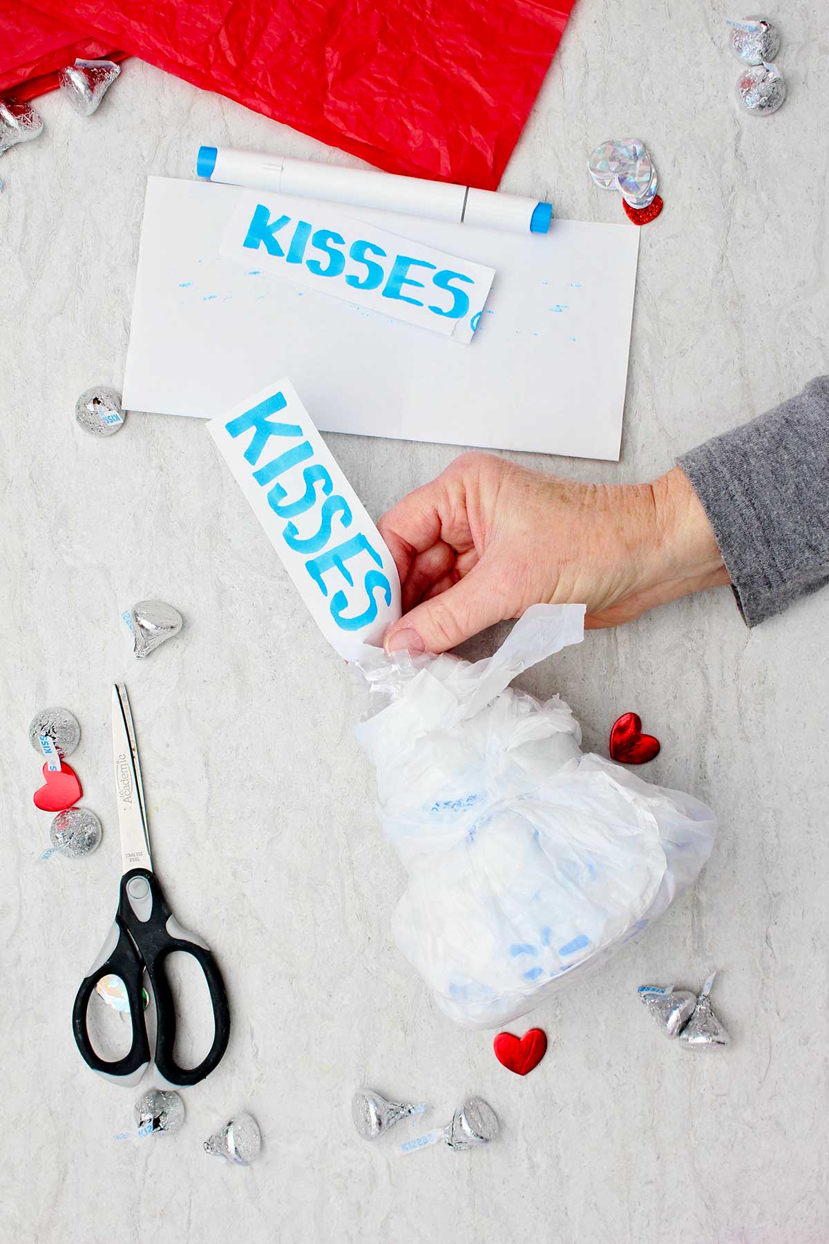 Pessoa colocando uma etiqueta escrita à mão que diz "kisses" no topo do gigante DIY Hershey Kiss.