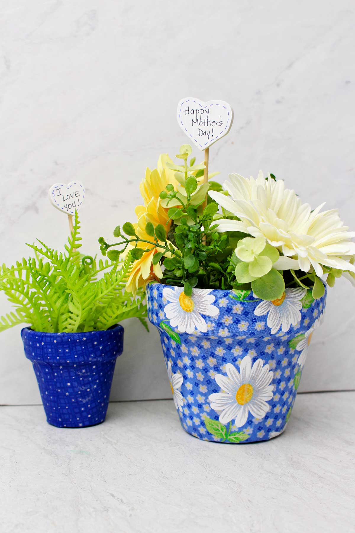 Vasos de flores decoupados com tecido preenchidos com flores de primavera e folhagens.