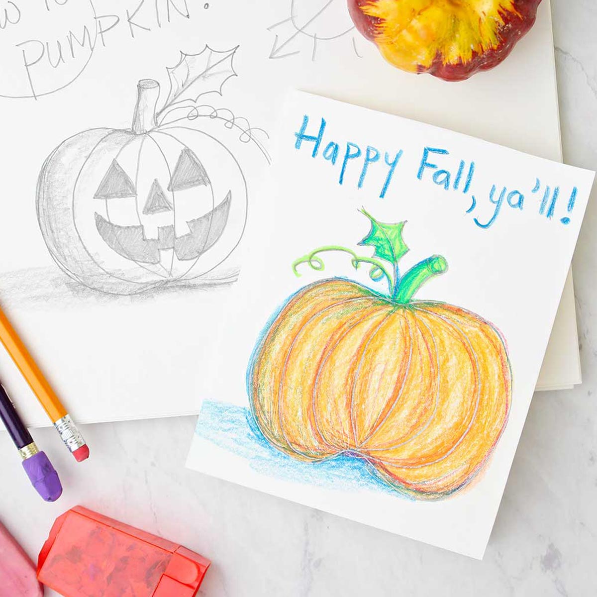 Um cartão de saudação com um esboço de abóbora colorida repousando sobre um esboço de lápis de jack-o-lantern. Materiais de desenho e coloração próximos.