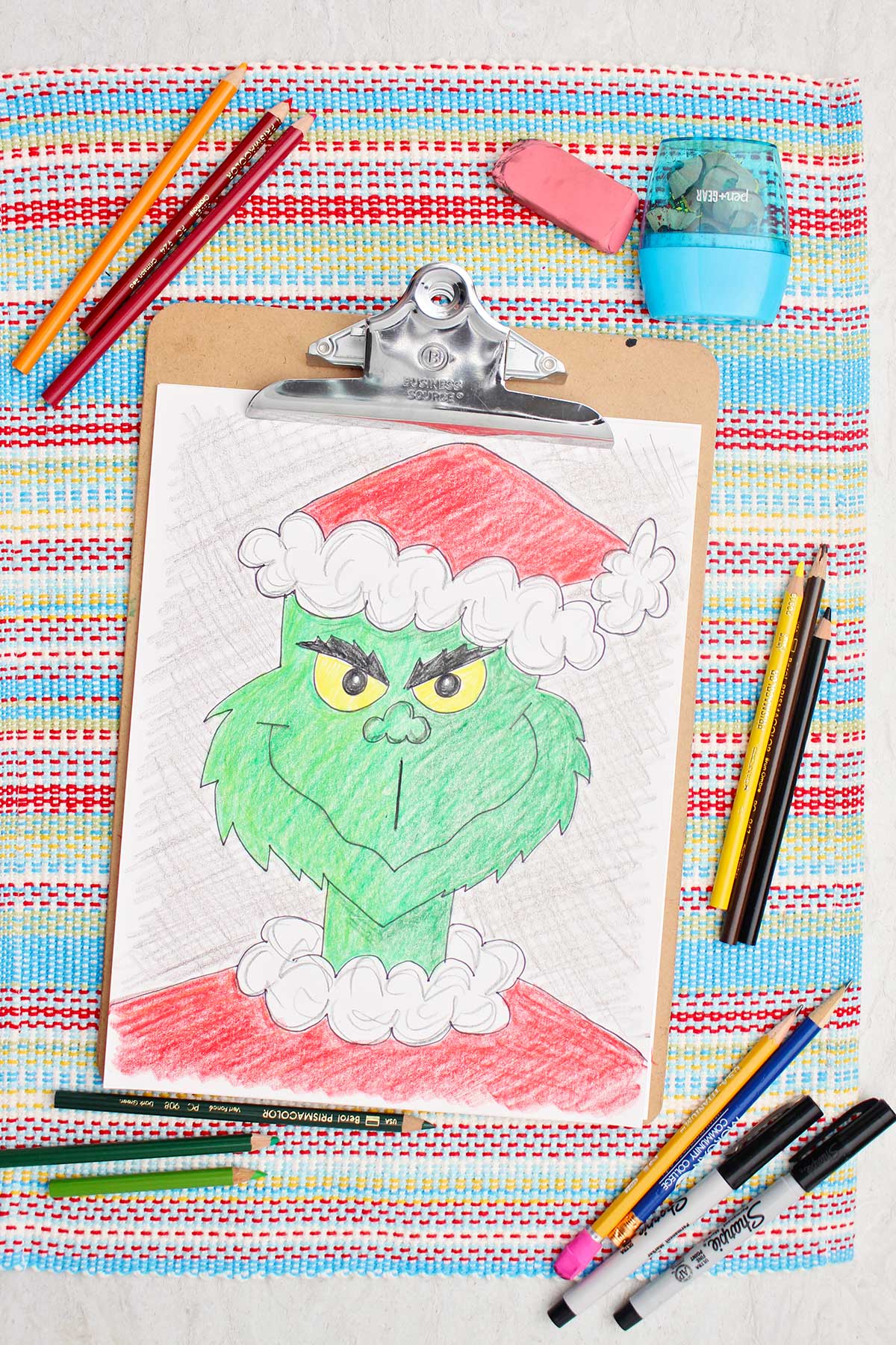 Versão colorida de um esboço do Grinch com lápis coloridos ao lado.