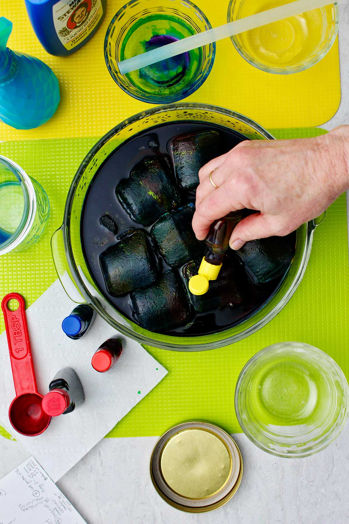 Mão pingando corante alimentar amarelo sobre blocos de carvão.