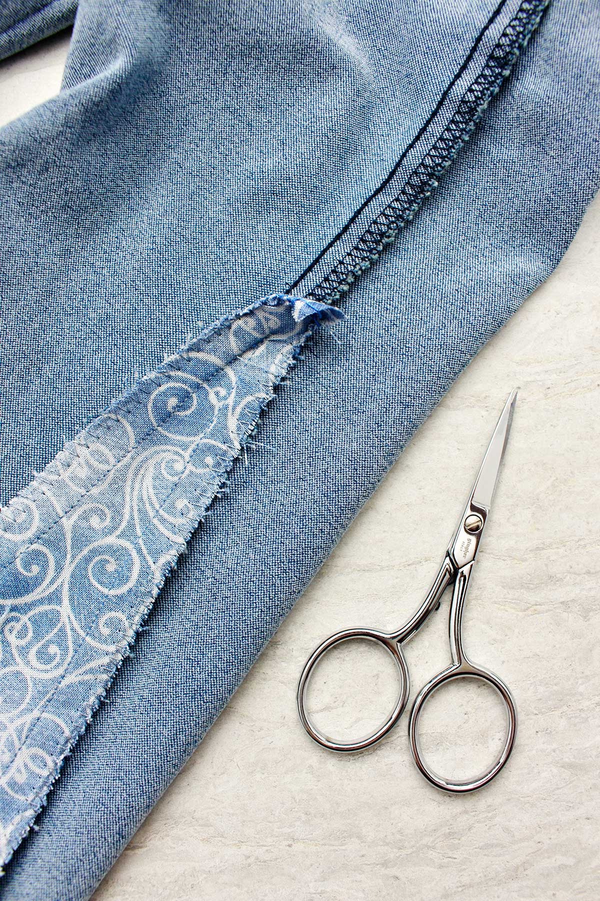 Close da parte de dentro do jeans do avesso com o pedaço de tecido costurado.