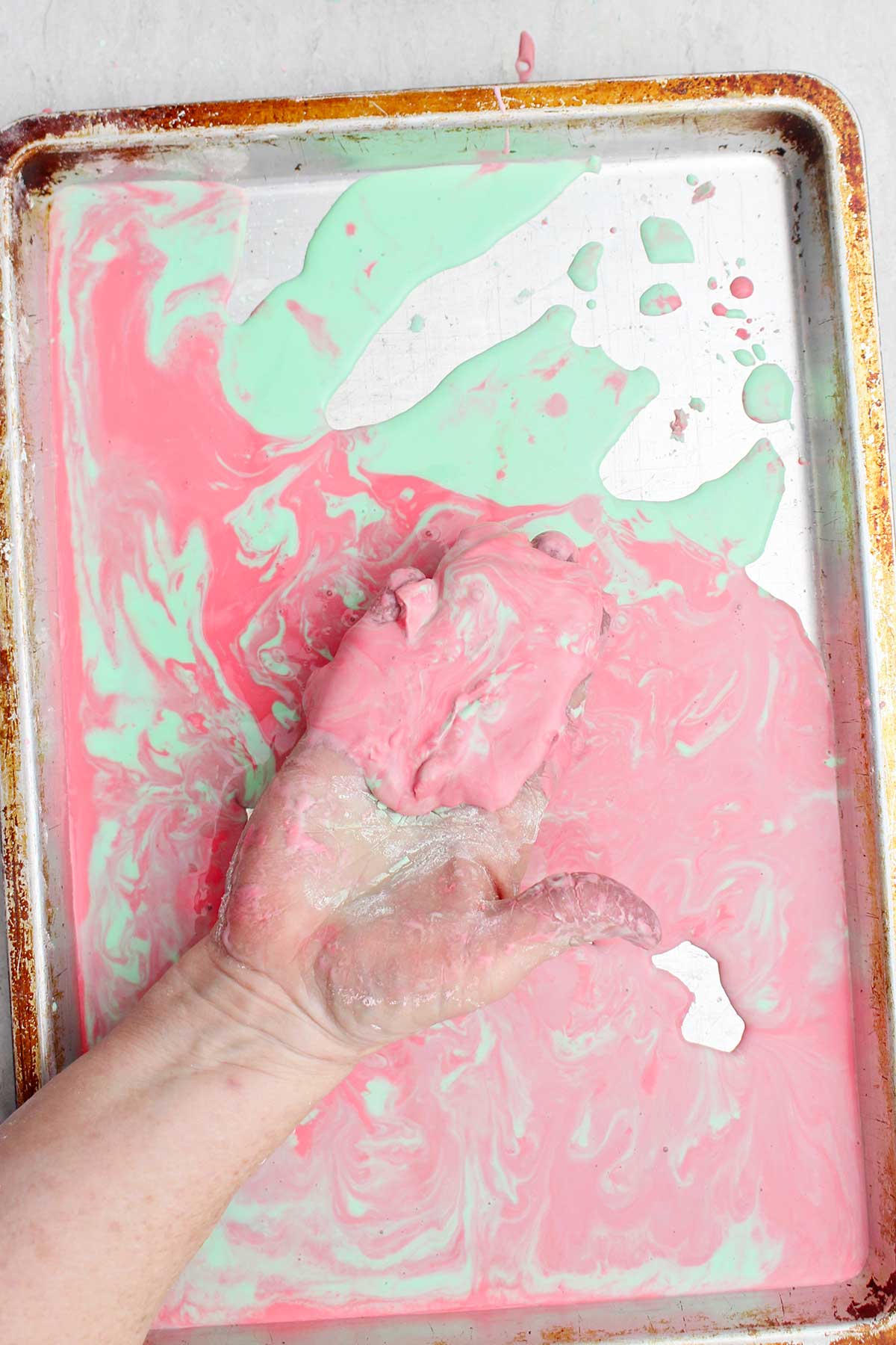 Uma pessoa brincando com uma versão mais líquida do oobleck em uma assadeira.