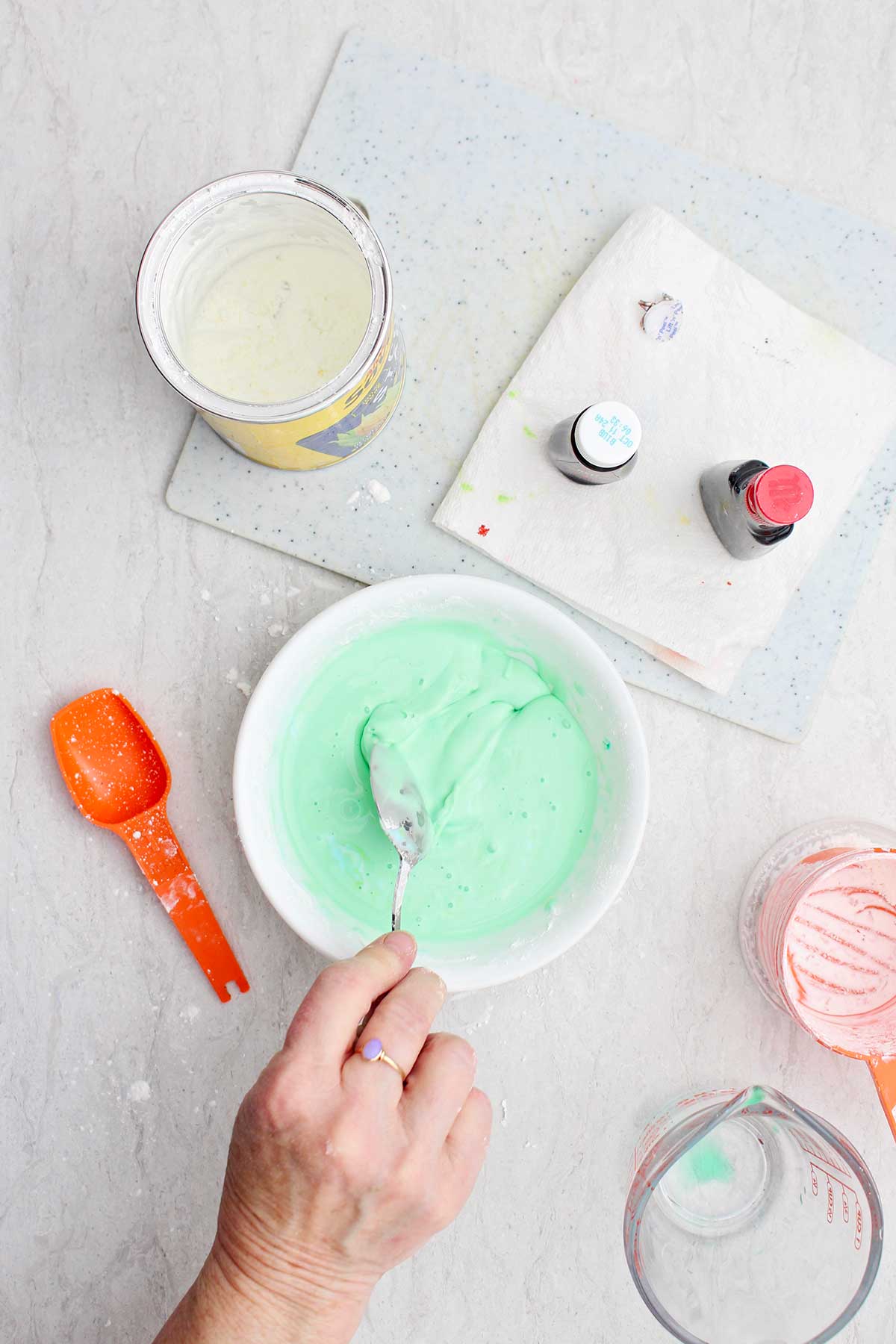 Uma pessoa misturando uma tigela verde clara de ingredientes para oobleck.