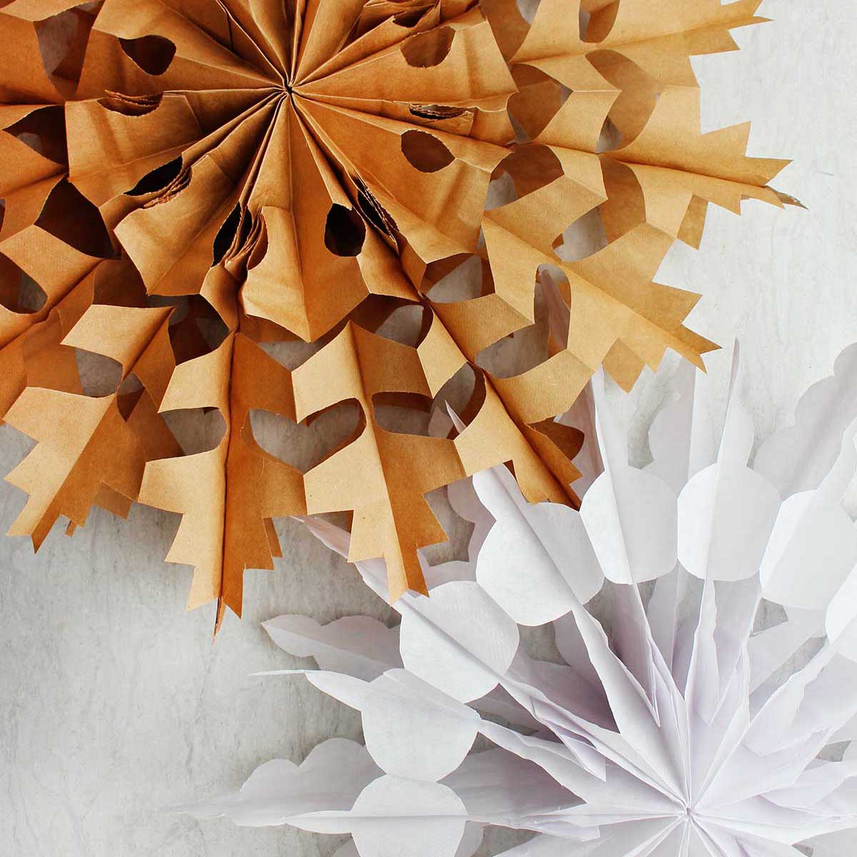 Dois flocos de neve de sacola de papel concluídos. Um marrom e um branco.