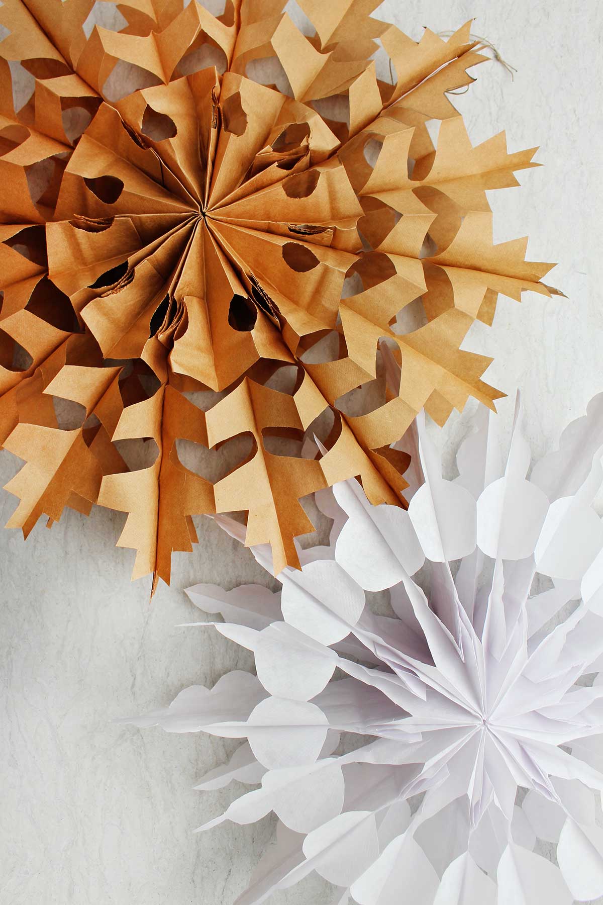 Dois flocos de neve de papel prontos. Um em marrom e um em branco.