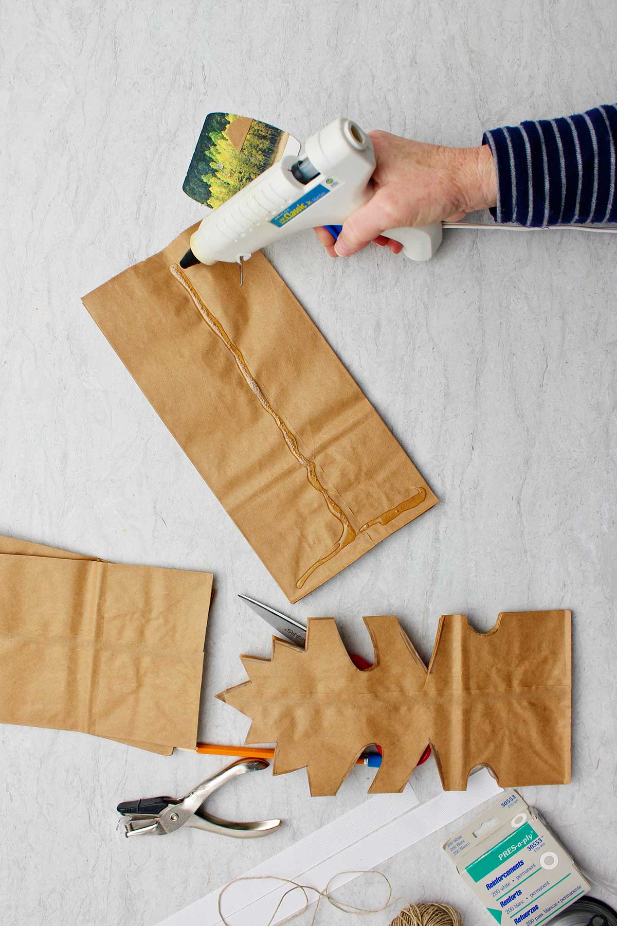 Mão colando sacos de papel marrons juntos antes de cortar.