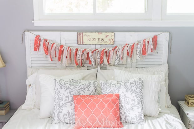 Um quarto com uma bandeira de tecido em coral e branco e almofadas