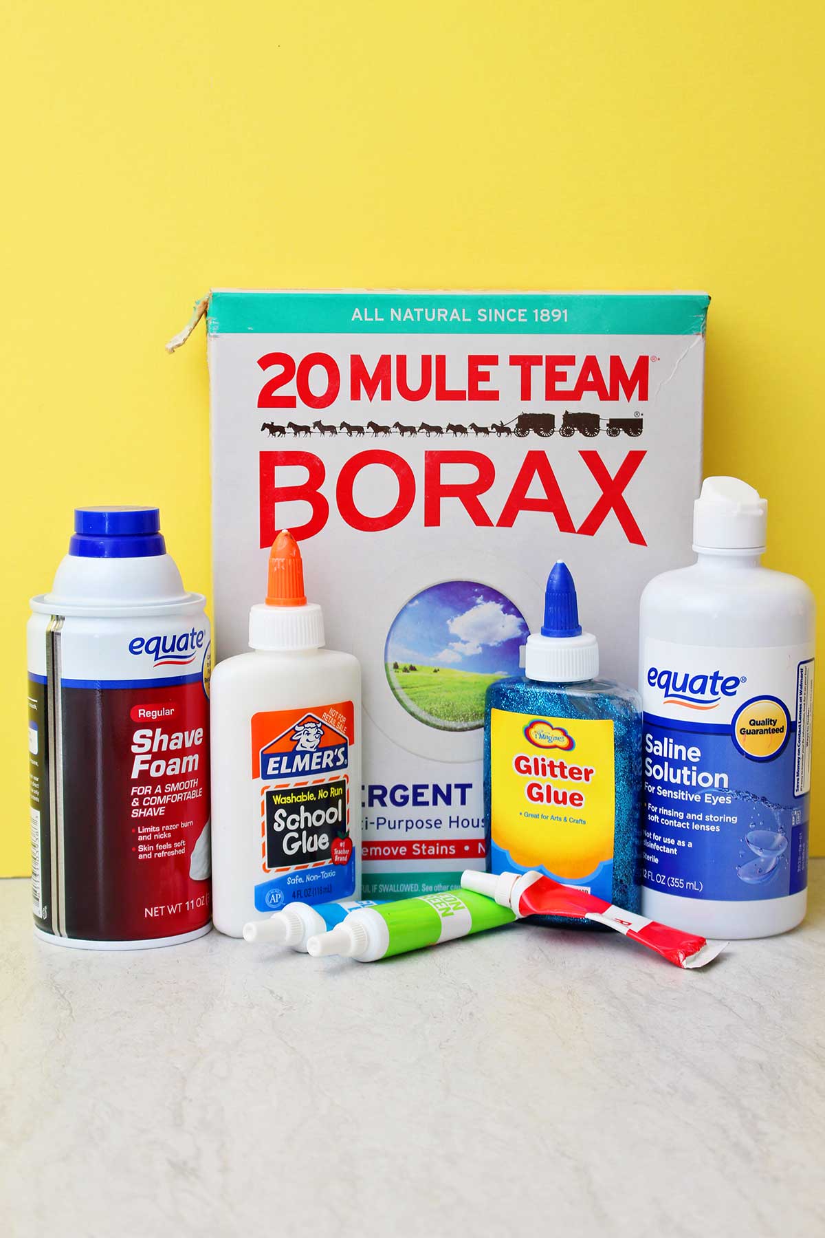 Todos os suprimentos necessários para fazer um lote de slime fofinho em um fundo amarelo.