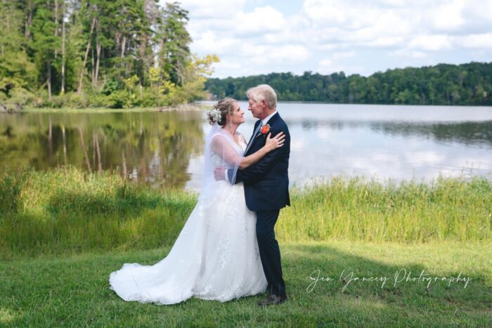 Casal mais velho em traje de casamento diante de um lago