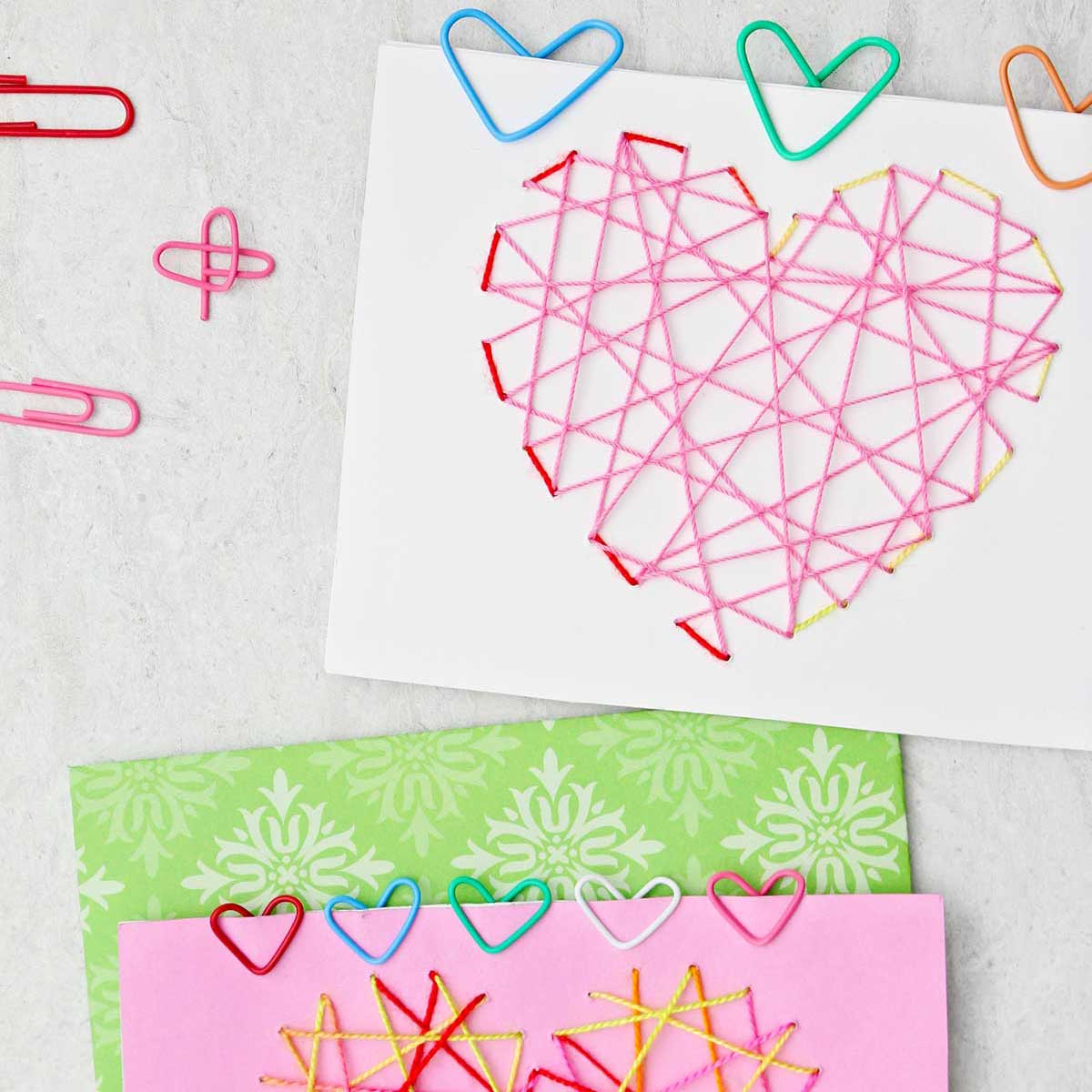 Dois cartões de Dia dos Namorados com clipes de papel coloridos em forma de coração presos a eles.