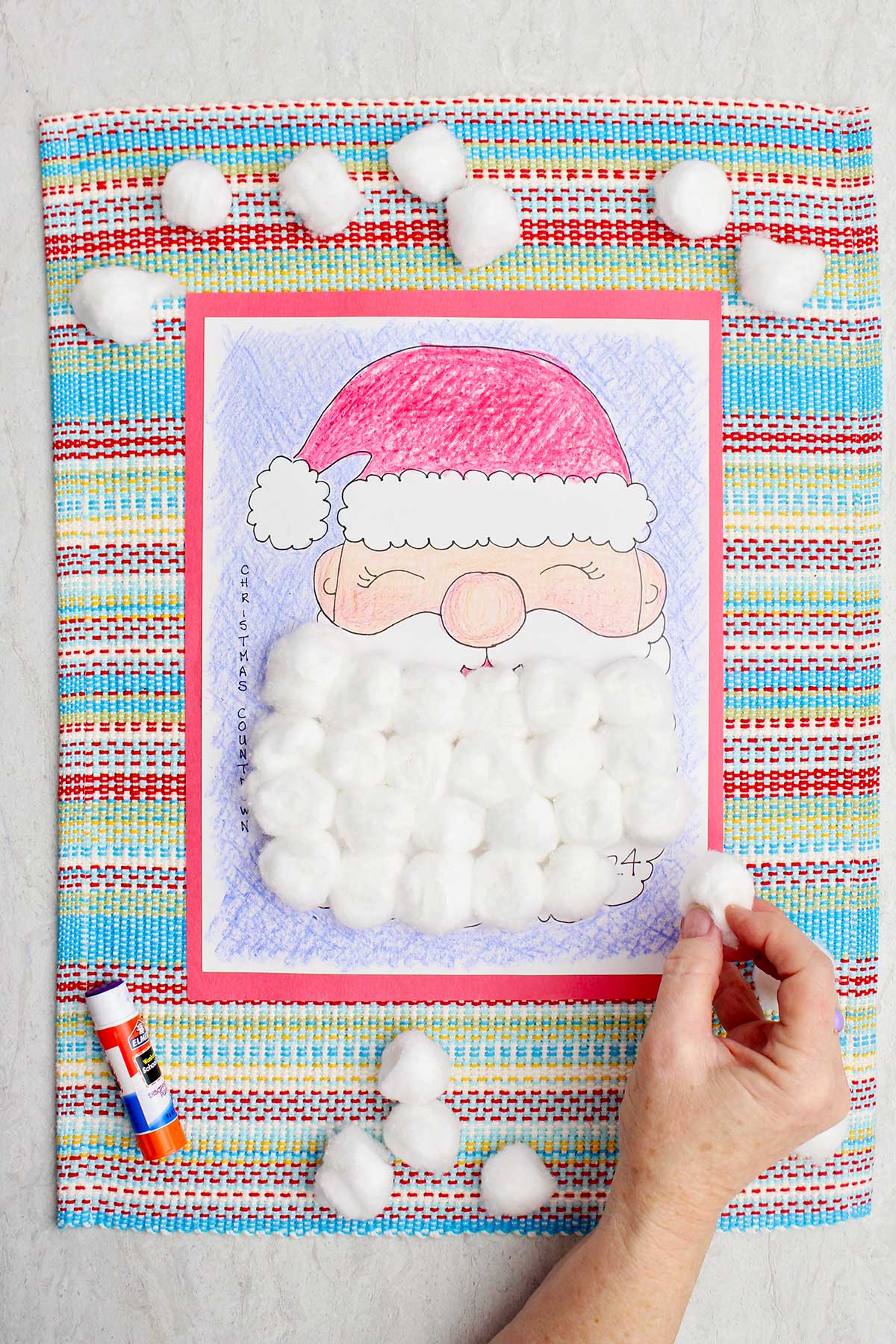 Uma pessoa colocando uma bolinha de algodão em um dia na barba do Papai Noel no calendário de contagem regressiva.