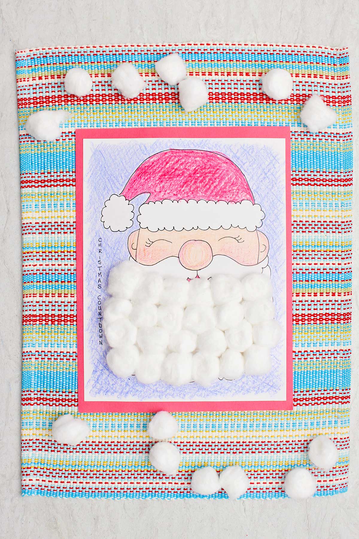 Um calendário de contagem regressiva de Natal completo, colorido com giz de cera e a barba do Papai Noel coberta com bolas de algodão.