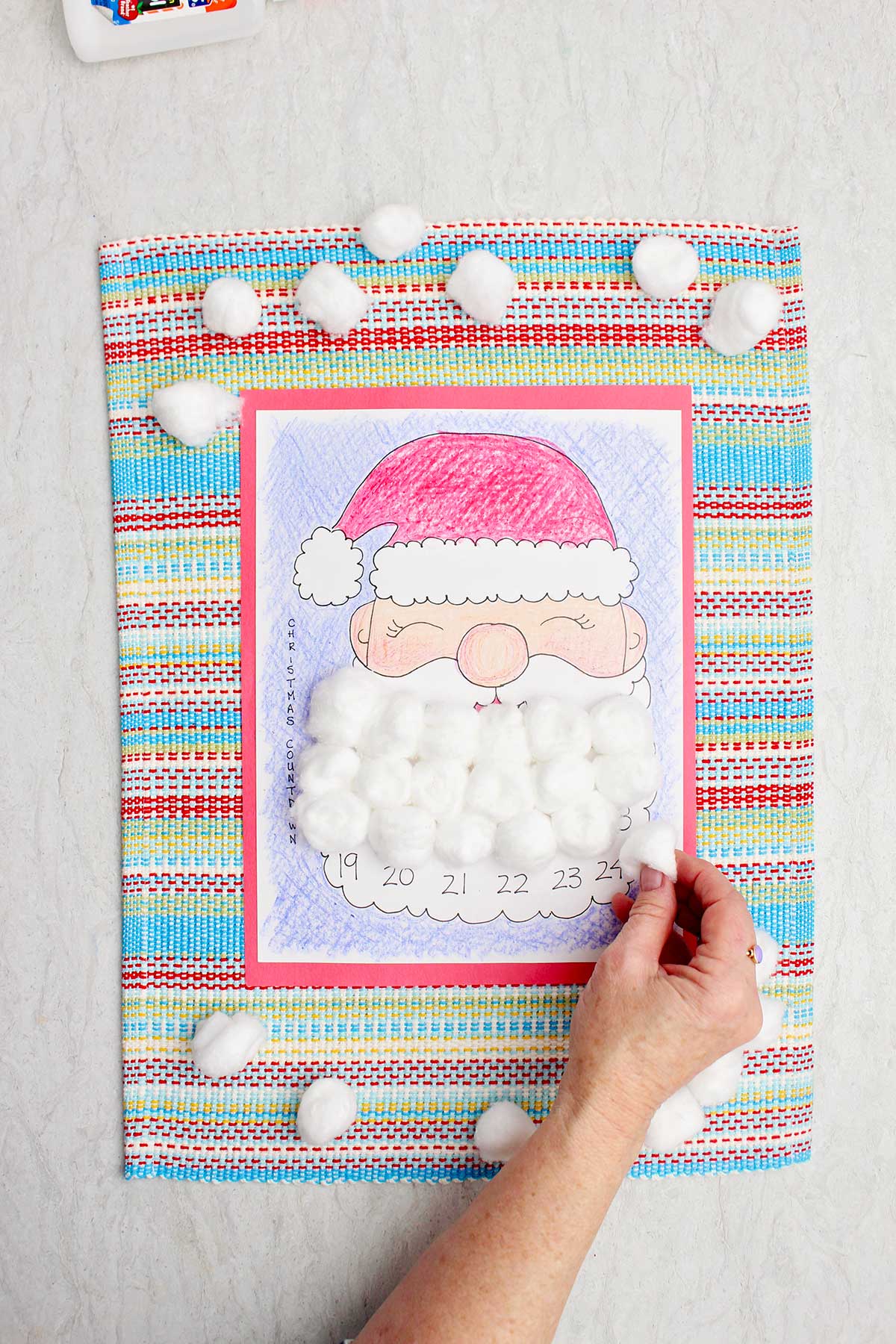 Uma pessoa colocando uma bolinha de algodão em um dia da barba do Papai Noel no calendário de contagem regressiva.