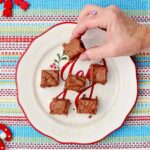 Uma pessoa pegando um pedaço de fudge de um prato de festa.