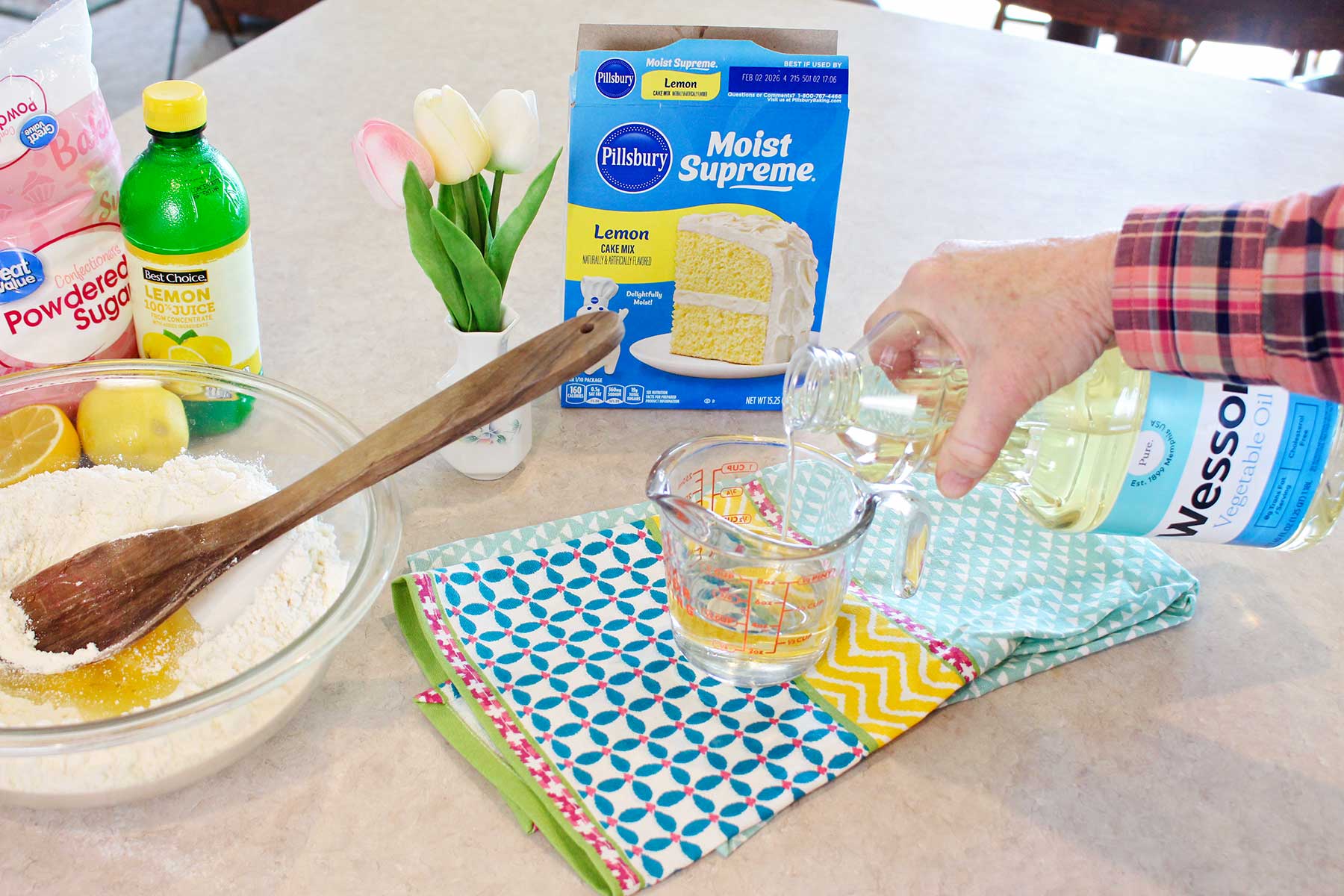 Uma pessoa medindo óleo vegetal para os biscoitos de mistura para bolo.