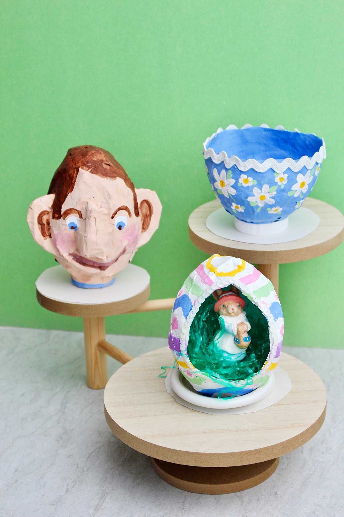 Três tipos diferentes de projetos de papel machê em pedestal de madeira.