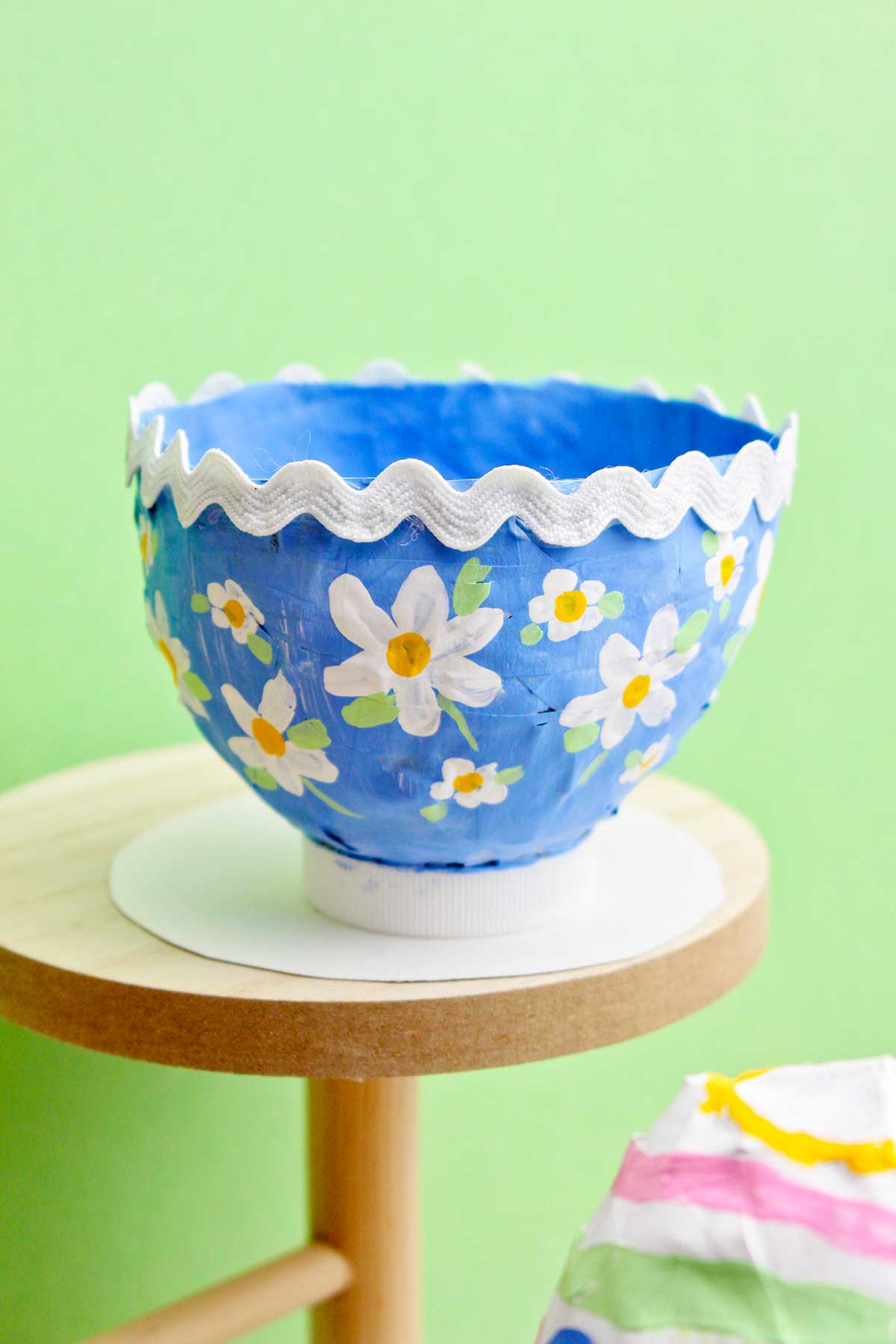 Uma bonita tigela de papel machê azul com flores pintadas e uma borda de rick rack.