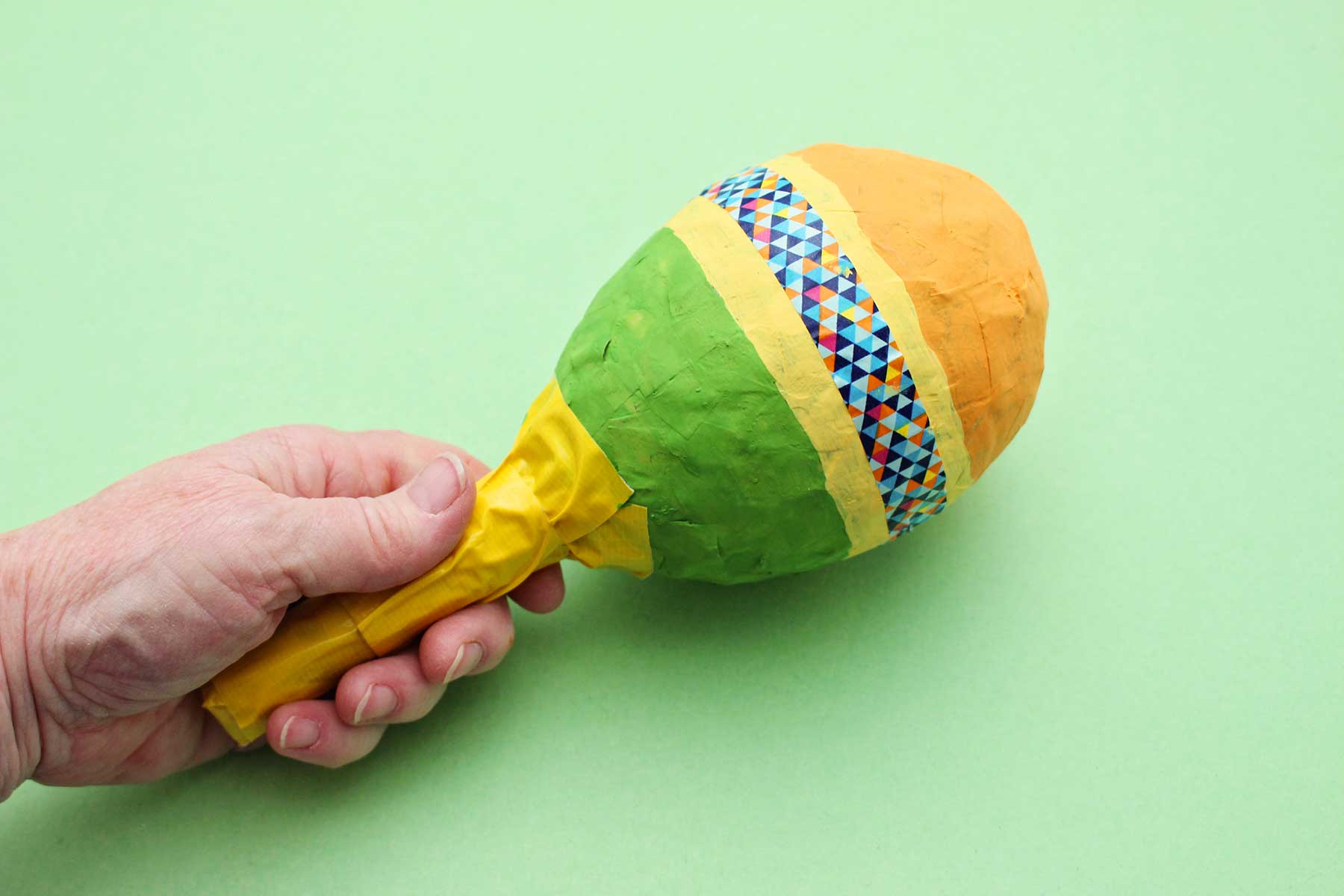 Uma pessoa segurando uma maraca de papel machê.