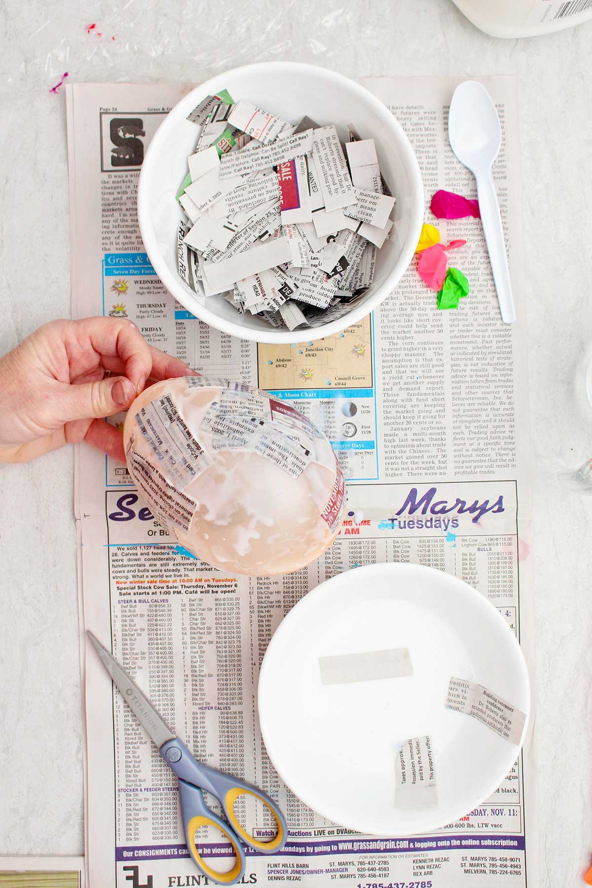 Uma pessoa segurando um pequeno balão sendo usado como molde para um projeto de papel machê.