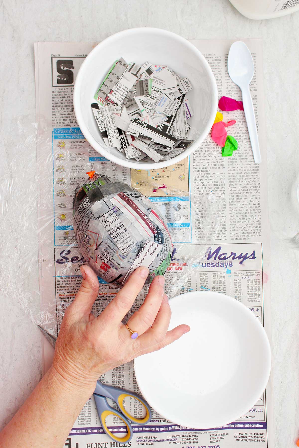 Uma pessoa pressionando pedaços de papel machê sobre um balão devidamente inflado.