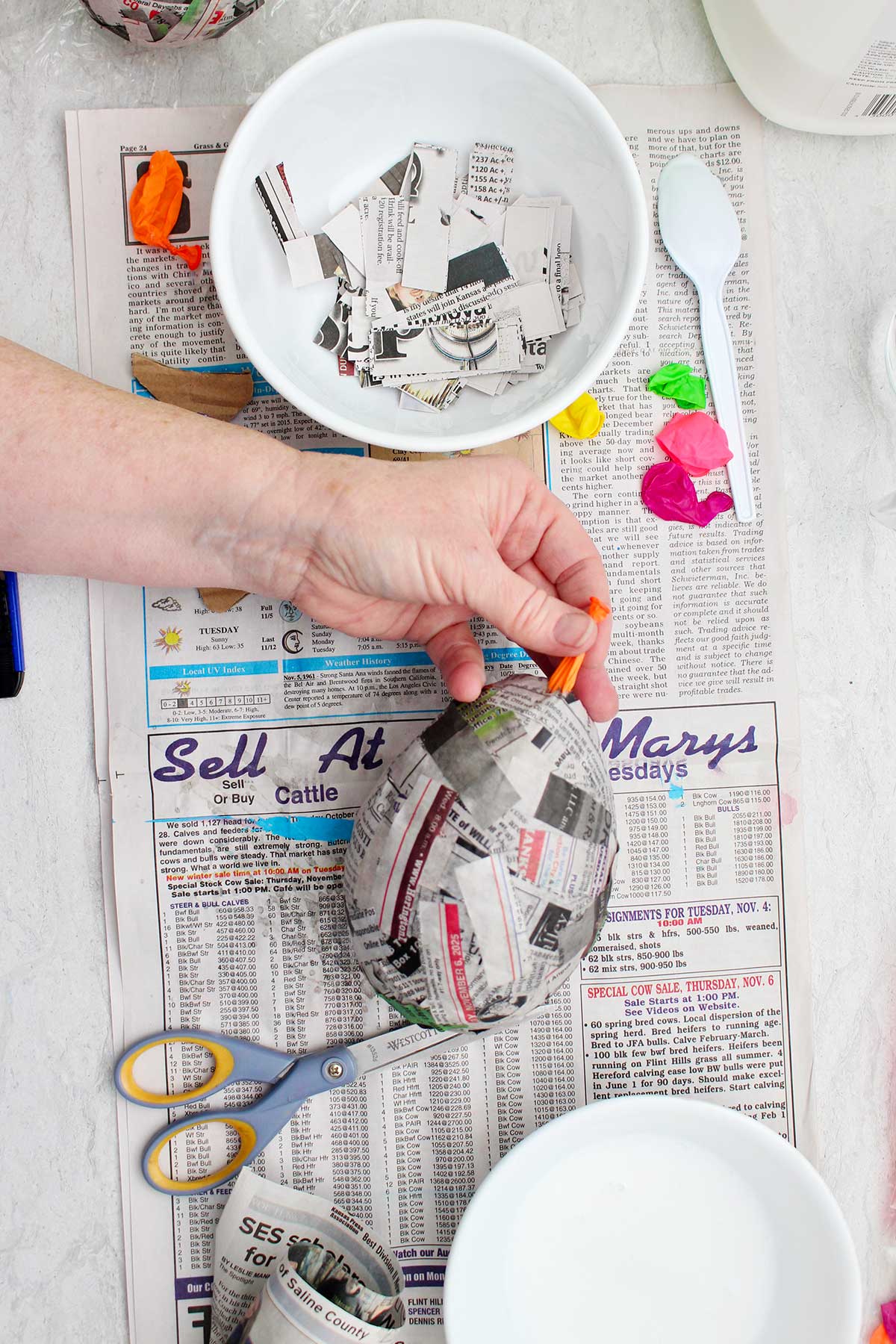 Uma pessoa puxando um balão estourado de um projeto de papel machê seco.