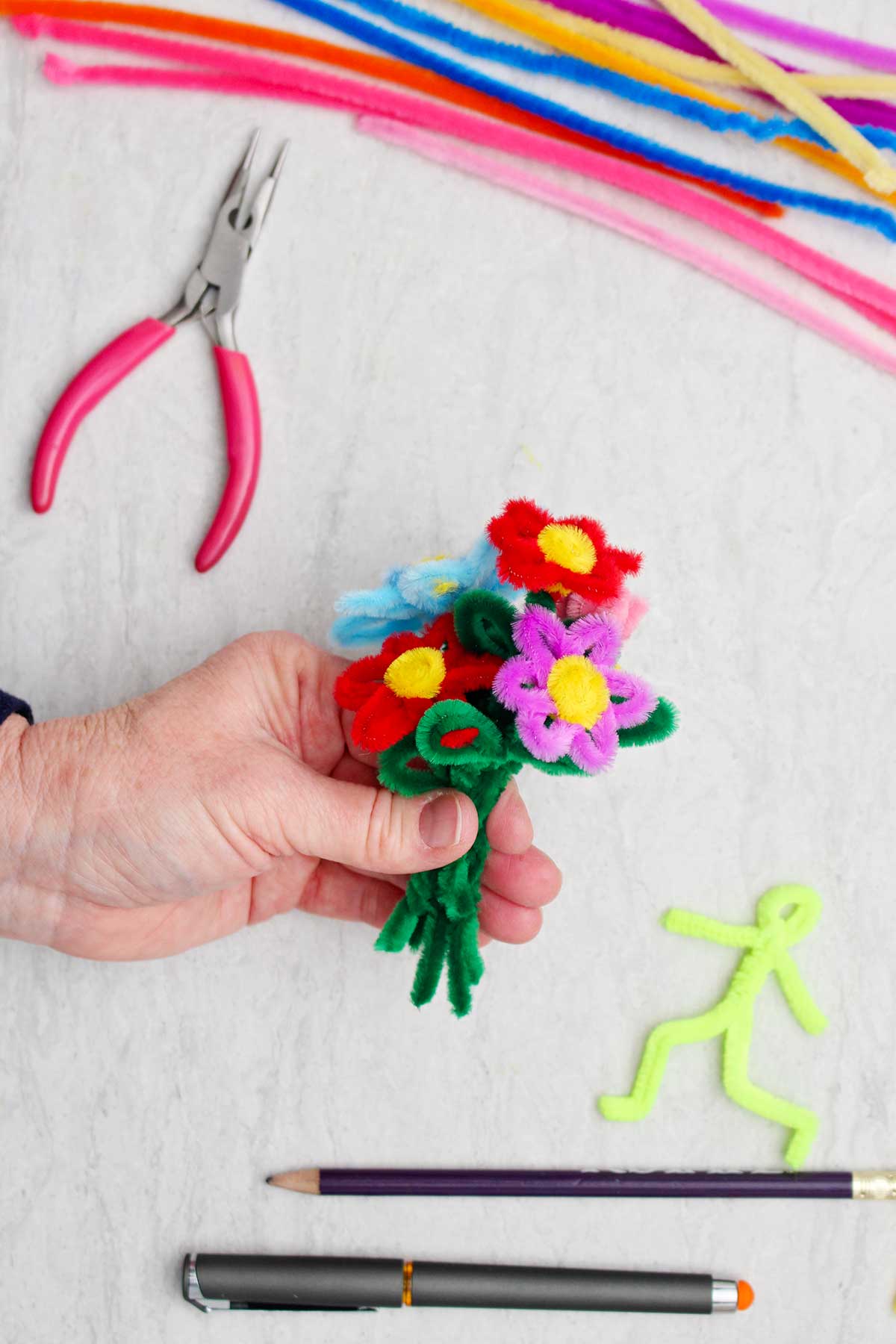 Uma pessoa segurando um buquê de flores de limpadores de pipe de várias cores.
