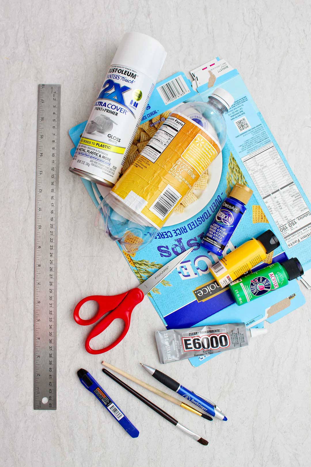 Suprimentos para um avião de garrafa plástica. Tinta spray branca, garrafa plástica de refrigerante vazia, caixa de cereal de papelão achatada, tintas, tesoura, régua e cola.
