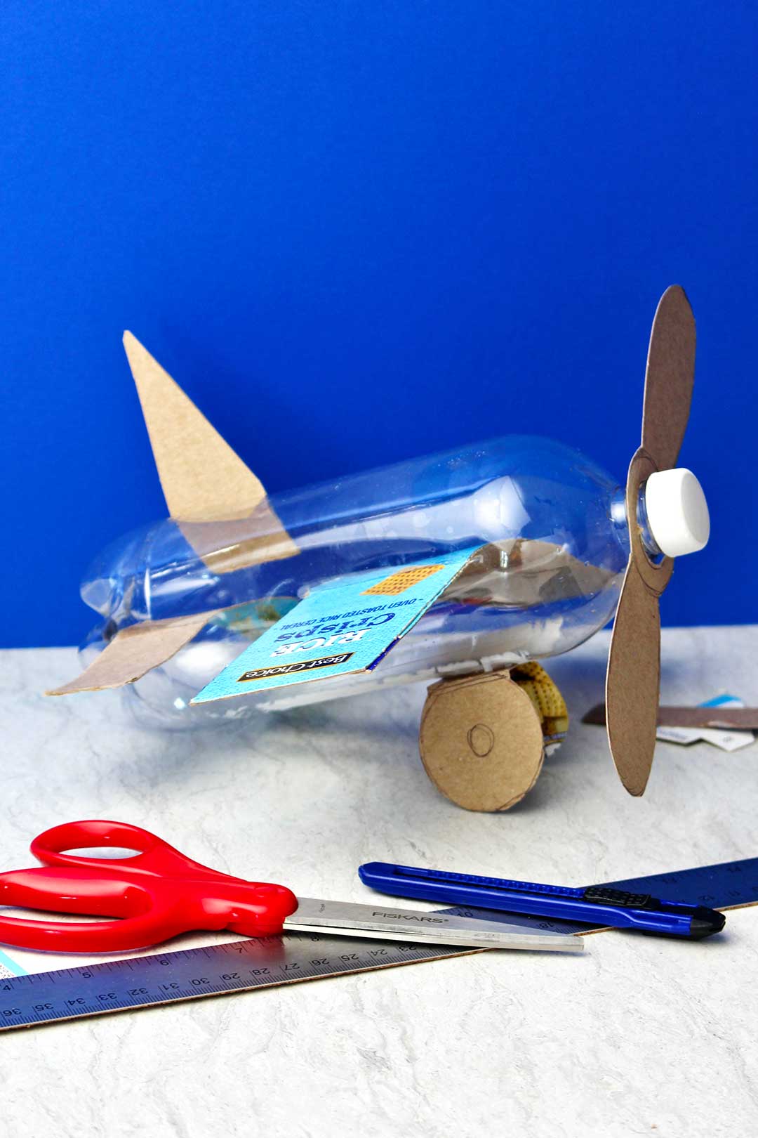 Avião de garrafa completo antes da pintura spray contra um fundo azul.